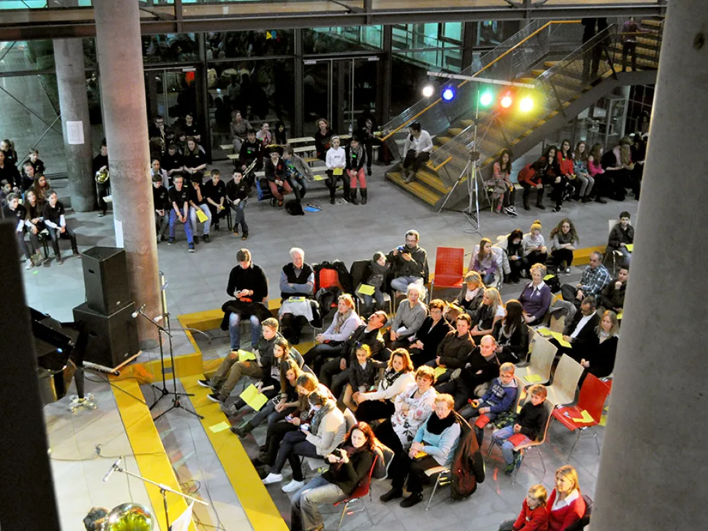 Publikum sitzt in Reihen im Foyer.